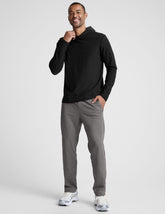 man wearing a black hoodie and gray pants on a white background.